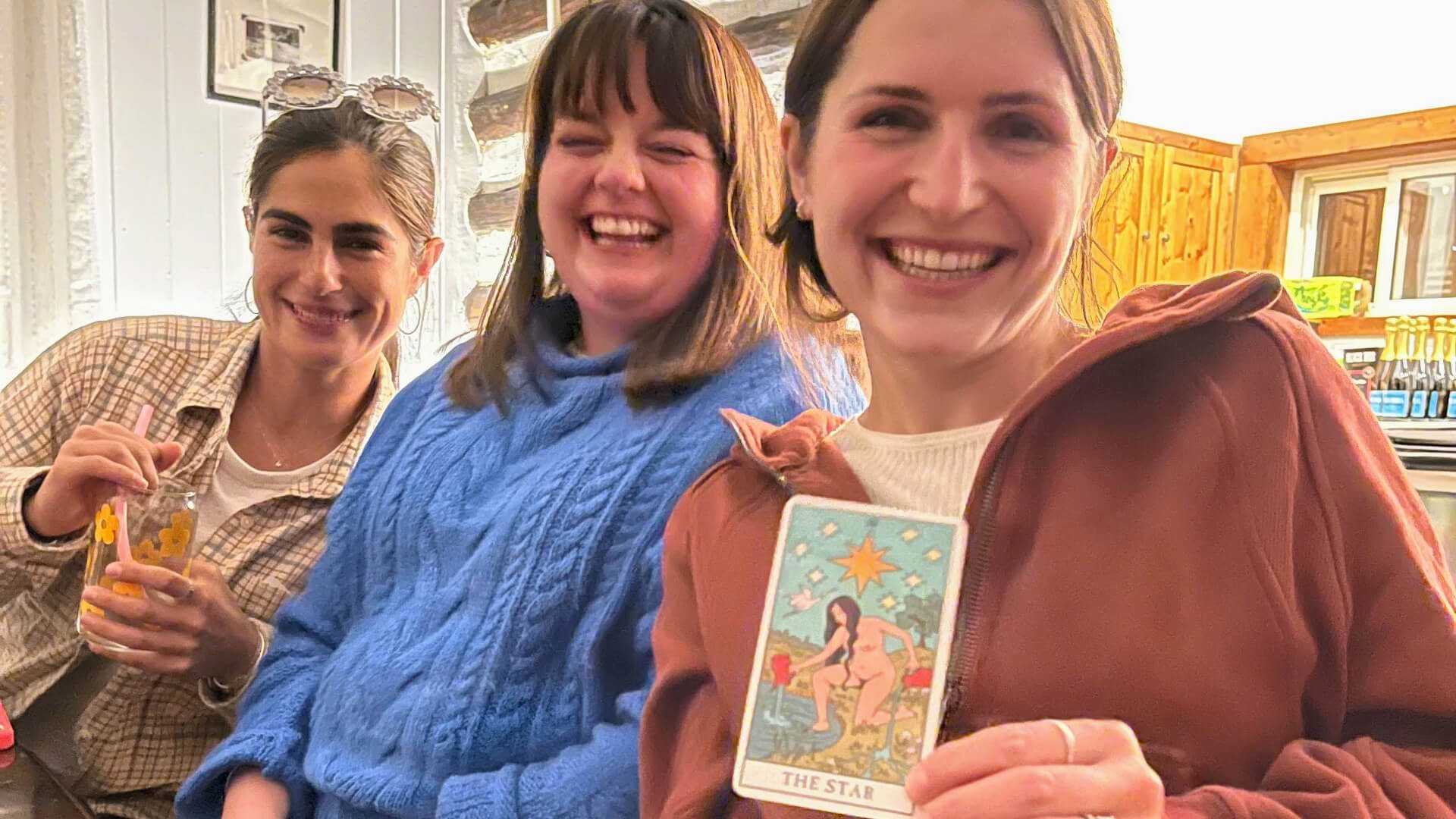Women smile as they choose tarot cards at their vacation rental in Asheville, NC.