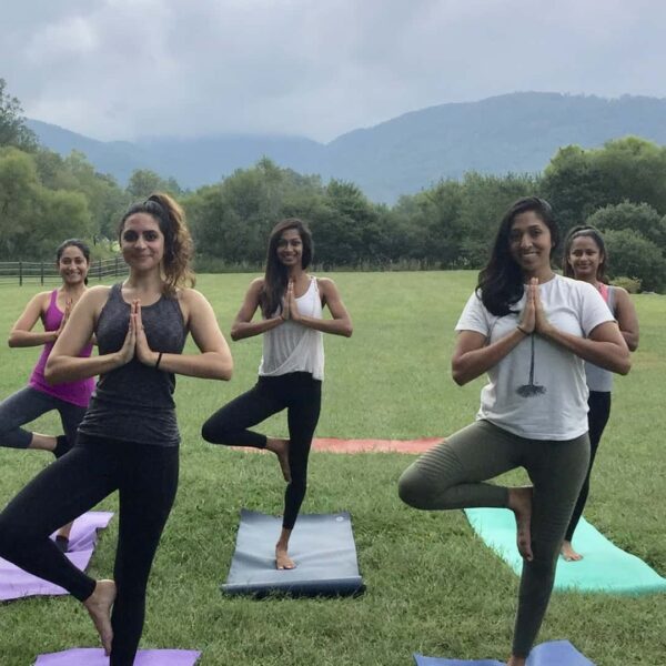 Bachelorette party in tree pose at private yoga class outdoors in the Asheville mountains.