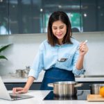11A woman cooks at home while following a virtual cooking class