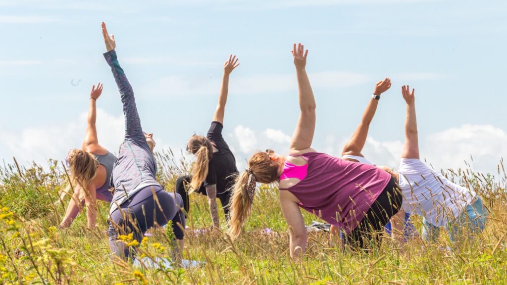 Women in yoga poses in field atop a mountain bald near Asheville, NC.