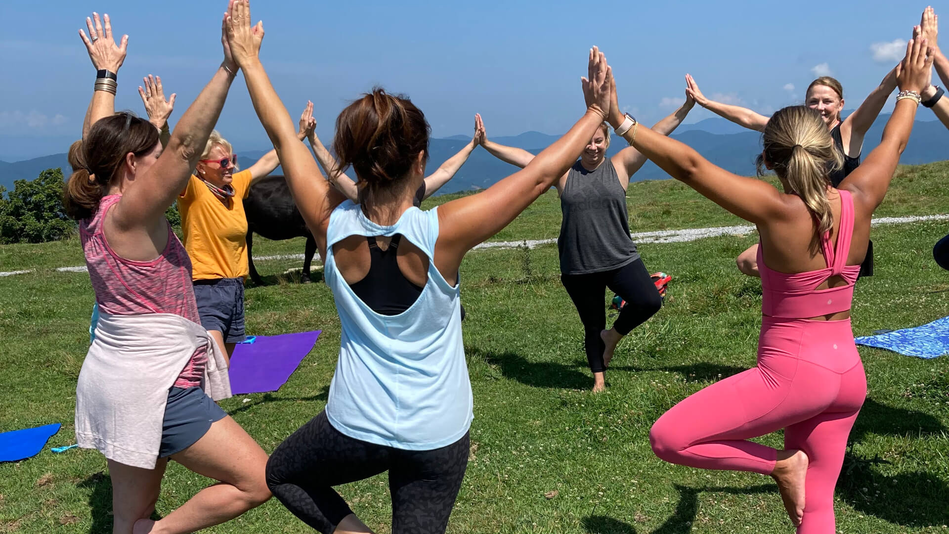 Women in circle on top of bearwallow mountain doing yoga hike class in Asheville, NC.