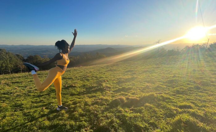 Woman in dancer pose during sunset yoga hike in Asheville, NC.