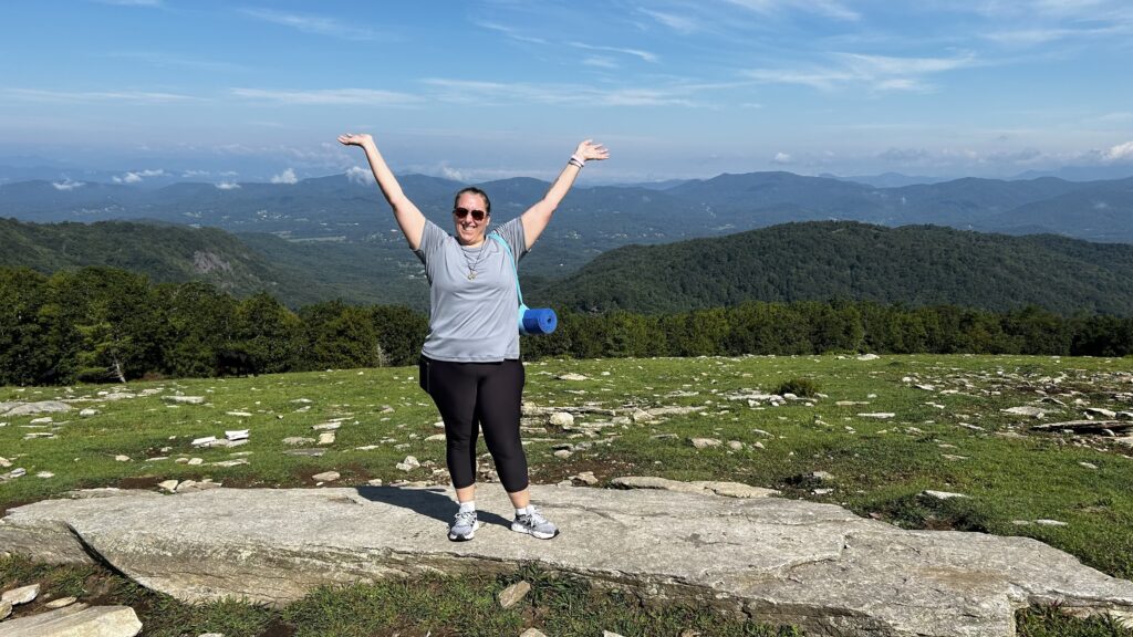Woman raising arms above head while on a mountain top