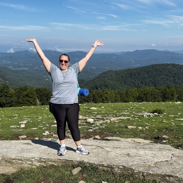 Woman raising arms above head while on a mountain top